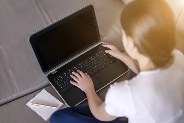 Young girl working on a notebook computer sitting on the bed in the house distance learning self education in terms of quarantine