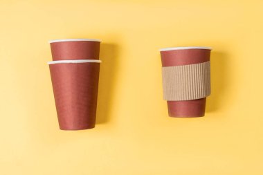 Pastel sarısı arka planda tek kullanımlık kağıt kahve. Düz yatış stili. Kağıt bardak kahve.