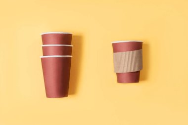 Pastel sarısı arka planda tek kullanımlık bir kahve fincanı düz, kağıt bir fincan kahve.