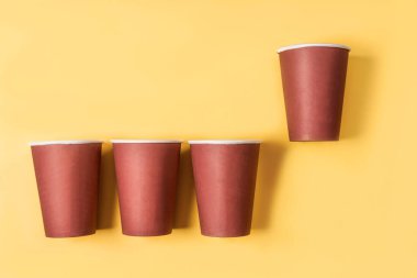 Pastel sarısı arka planda tek kullanımlık bir kahve fincanı düz, kağıt bir fincan kahve.