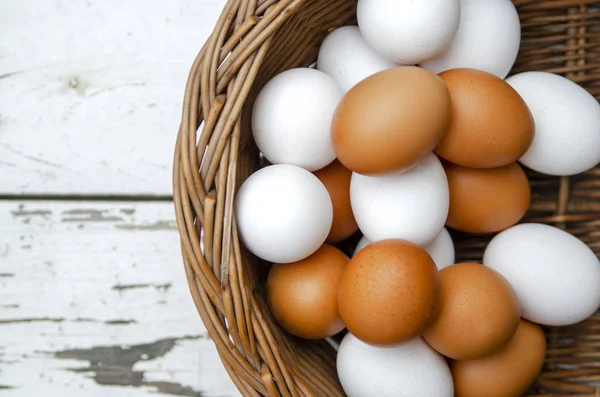 Different colors of chicken eggs in basket, top view. Pile of white and orange fresh raw eggs.