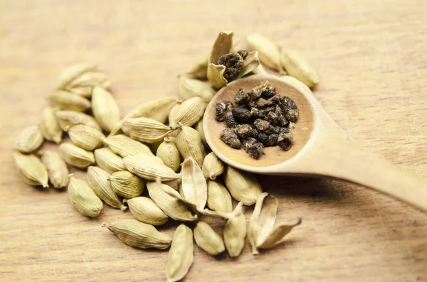 Masadaki tahta kaşıkta kakule tohumları.