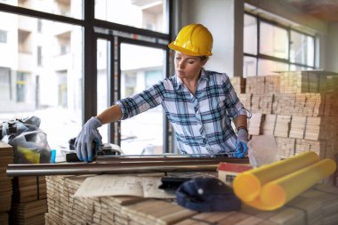 İnşaat alanında miğferi olan kadın mimar. İnşaat mühendisi kadın. Evi yenilemek için gerekli malzemeleri kontrol ediyor.