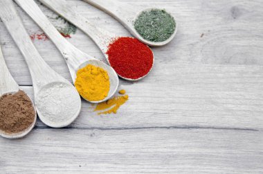 Beyaz arka planda ahşap kaşıklarda çeşitli baharatlar