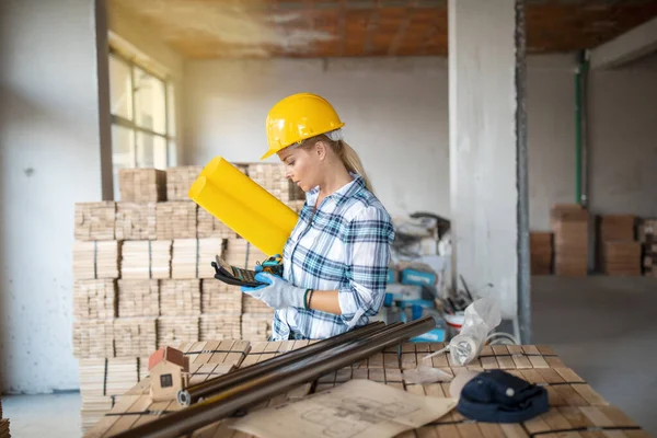 İnşaat alanında miğferi olan bitkin bir mimar. Evi yenilemek için kadın inşaat mühendisi kontrol materyali