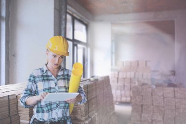 İnşaat alanında miğferi olan bitkin bir mimar. Evi yenilemek için kadın inşaat mühendisi kontrol materyali.