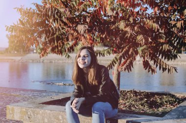 Genç bir kadın parkta bankta oturuyor.