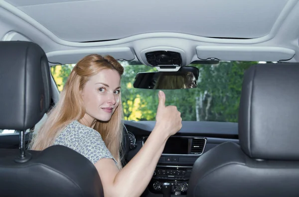 車を運転しながら奥のスマートフォンを使う若い女性は — ストック写真