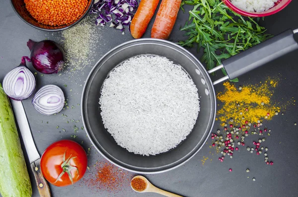 Sebzeler, baharatlar ve kızartma tavası düz siyah masa üzerinde. Üst görünüm aşçılık dersleri konsepti..