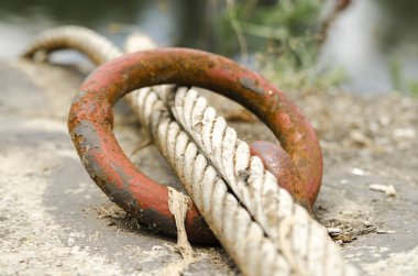 Rope on old rusty ship ring in Belgrade marine. Close up view of ring anchor and cable. Old Frayed boat rope as a Nautical background.