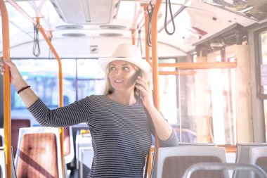 Otobüste cep telefonu kullanan bir kadın. Toplu taşımada modern sarışın kadın saçı 