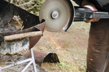 Paslı metal yapımını öğüten adam, evdeki eski barbeküyü tamir eden adam.