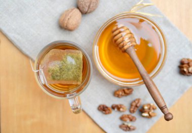 Tahta kaşıklı bal kasesi ve mutfak havlusunda ceviz. Grip salgını sırasındaki sağlıklı atıştırmalıklar veya ilaçlar. Kış mevsimi diyet tedavisi.