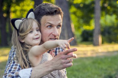 Father and adorable toddler girl daughter play and hug in the park clipart