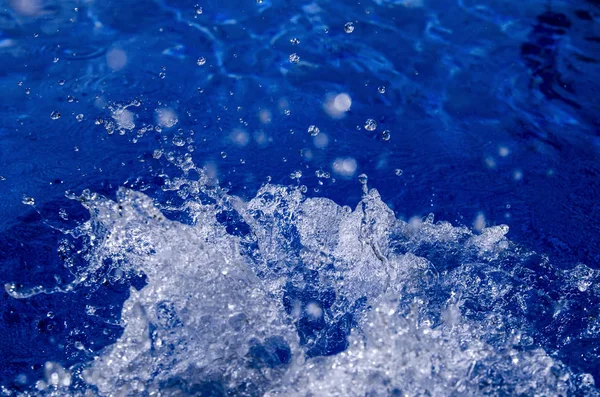 Water splash isolated on blue natural background.Close up view of aqua foam and air bubbles