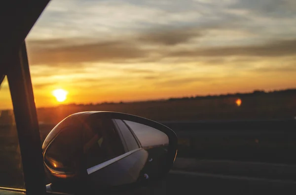 Driving car in sunset.Beauty on sky going on trip at night. Rear view mirror of the car on the road