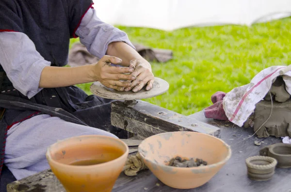 Woman working with fresh wet clay on pottery wheel.Female hands make ceramic plate in old fashion way outdoors