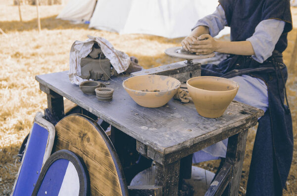 Woman working with fresh wet clay on pottery wheel.Female hands make ceramic plate in old fashion way outdoors