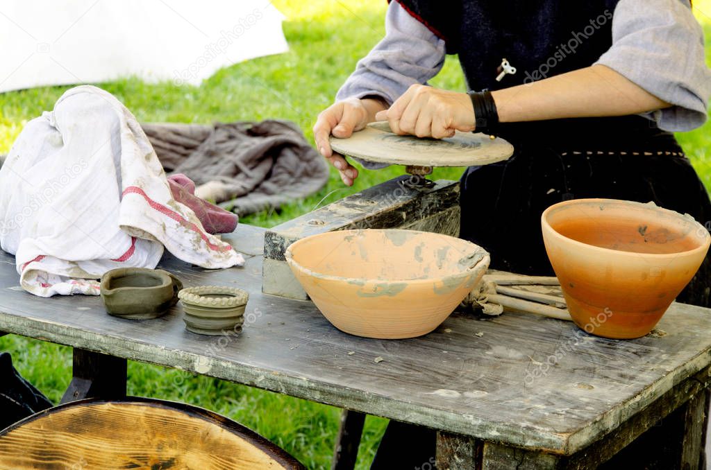 Woman working with fresh wet clay on pottery wheel.Female hands make ceramic plate in old fashion way outdoors