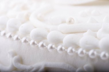 Beyaz Düğün Pastası detayı. Sevimli, kıvrımlı ve dekoratif incilerle yakın plan.