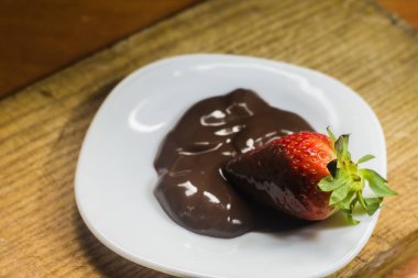 Beyaz tabakta çikolatalı çilekli tatlı.