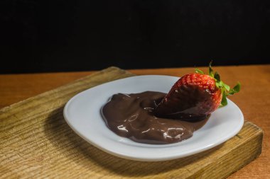 Beyaz tabakta çikolatalı çilekli tatlı.