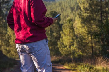 Ormanda cep telefonu kullanan bir kadının ellerine yakın çekim.
