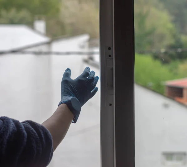 hands in women\'s gloves spain at window preventing bacteria from coronavirus germs
