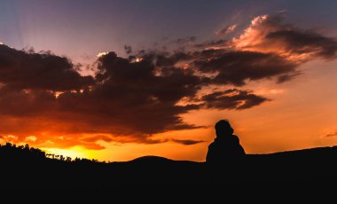 Gün batımında dağın tepesinde bir yürüyüşçü. Yüksek dağlardaki dağ manzarasına hayran bir kadın.