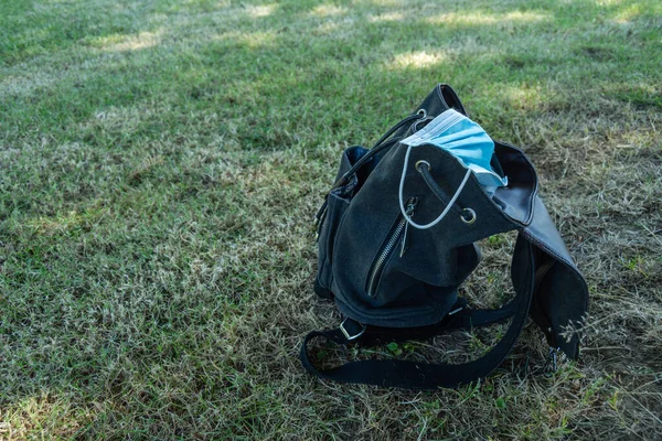 Obrázek Modrých Chirurgických Masek Černém Batohu Zelené Travnaté Podlaze Covid19 — Stock fotografie