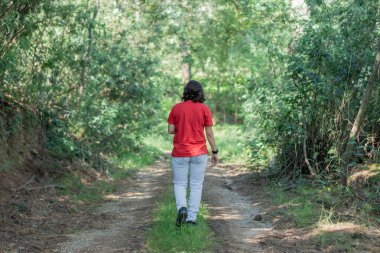 Koronavirüs salgını sırasında parkta ya da ormanda yürür. İnsanların sosyal mesafesi. Kırmızı bahar tişörtü giymişti.