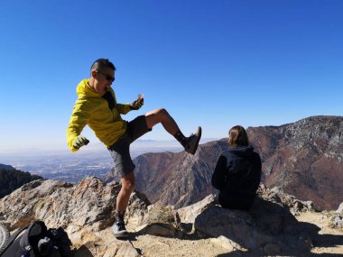 Asyalı bisikletçi, Sardalya Tepesi 'nin manzarasının tadını çıkaran beyaz bir kadınla şakalaşıyor.