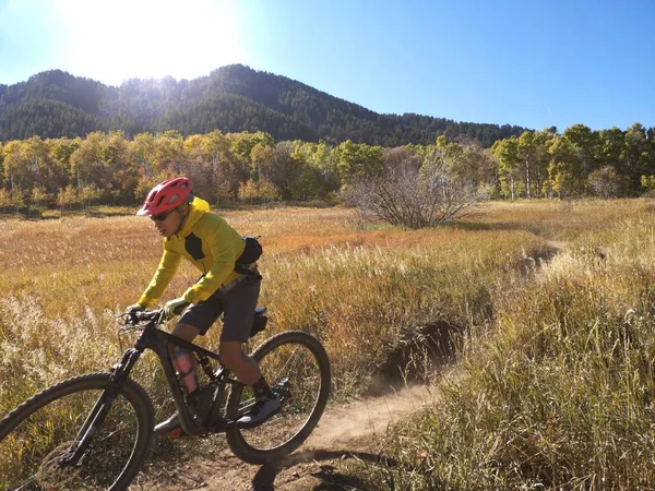 Asian guy with yellow jacket riding a bike around Sardine Peak Trailhead
