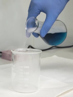 Mavi bir sıvı ve kuru buzla dolu bir matara şişeye dökülüyor.
