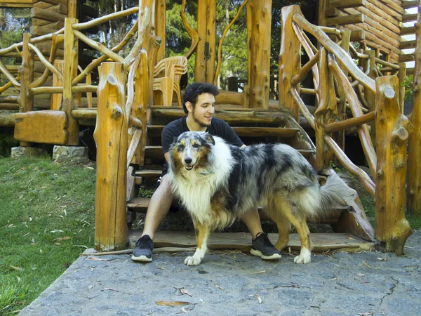 Молодой кавказский мужчина ласкает трехногую грубую собаку-колли — стоковое фото