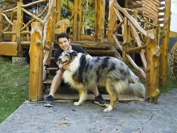 Молодой кавказский мужчина ласкает трехногую грубую собаку-колли — стоковое фото