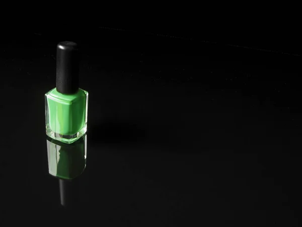 Zielony lakier do paznokci butelka na czarnym tle z refekcją. Poziomy. — Zdjęcie stockowe