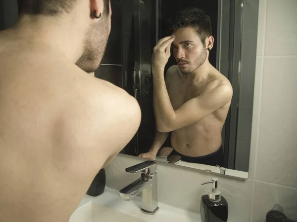 Potret remaja tampan Kaukasia refleksi dari cermin, membersihkan wajahnya dengan riasan riasan kapas — Stok Foto