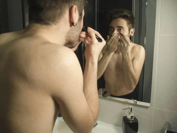 Potret remaja tampan Kaukasia refleksi dari cermin, menempatkan make-up, menggunakan tas remover — Stok Foto
