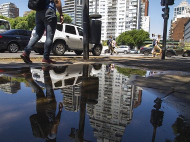 Parque Avellaneda, Buenos Aires, Arjantin; 27 Aralık 2019: Bir su birikintisi üzerindeki insanlar, arabalar ve binalar.