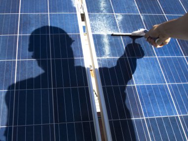 El ve gölge güneş panellerini cam silecekle temizliyor. Alternatif elektrik kaynağı, sürdürülebilir kaynak kavramı.