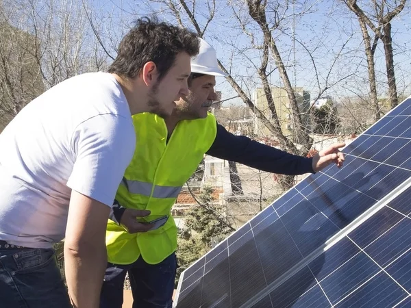 Kafkasyalı deneyimli teknisyen güneş panelleri dışında genç müşterisiyle konuşuyor. Alternatif elektrik kaynağı, sürdürülebilir kaynak kavramı.