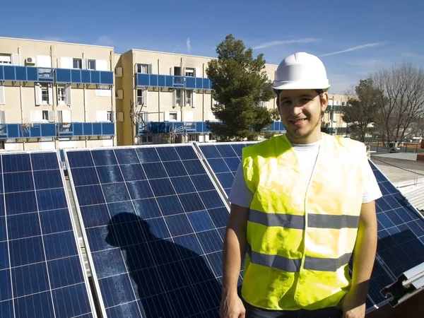 Caucasian attractive young technician looking at the camera beside the solar panels. Alternative electricity source, sustainable resource concept.
