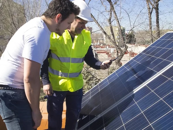 Kafkasyalı deneyimli teknisyen güneş panelleri dışında uygulamayı genç müşterisine anlatıyor. Alternatif elektrik kaynağı, sürdürülebilir kaynak kavramı.