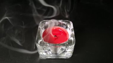 Rüzgar kırmızı bir mum söndürdü. Tüttür. Siyah arkaplan.