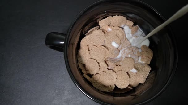 Latte Versato Una Ciotola Nera Con Cereali Sani Fondo Nero — Video Stock