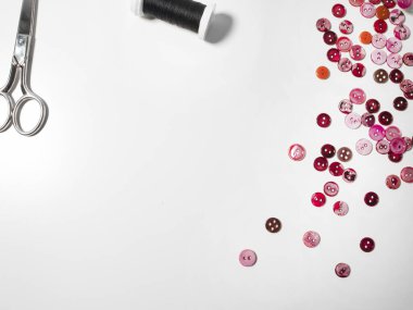 Beyaz arka planda pembe düğmeler, iplik ve makas. Dikiş ve zanaat konsepti.