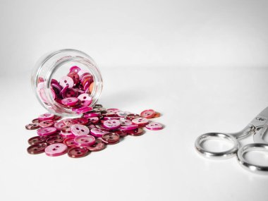 Beyaz arka planda pembe düğme ve makas dolu cam kavanoz. Dikiş ve zanaat konsepti.