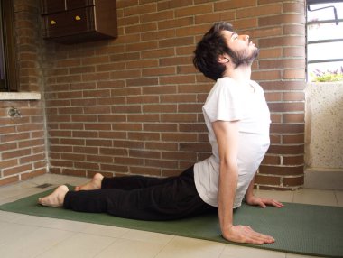 Genç yakışıklı beyaz adam yoga yapıyor, esniyor. Ev konsepti alıştırması.