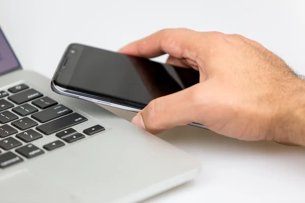 Bir dizüstü bilgisayarda telefon yerleştirerek adam